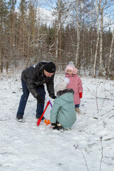 Little girls with her grandfather walk in a snowy forest, have fun together