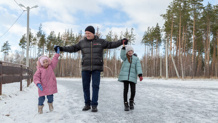 Little girls with her grandfather walking in park on snowy winter day