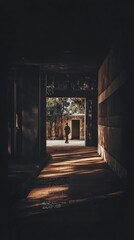 Obraz premium Shadowy hall person walks into bright courtyard
