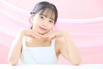 Obraz premium ピンク背景で撮影をした若い女性の爽やかな美容イメージ