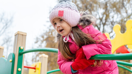 Little girl playing on playground in winter