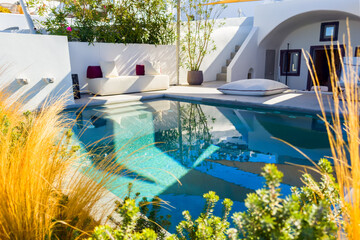 Santorini island, Greece. Luxury swimming pool with blue water and flowers.