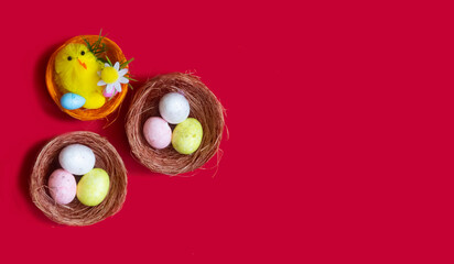 Lots of Easter eggs and a toy chicken in nests on a red background. Easter concept, close-up.