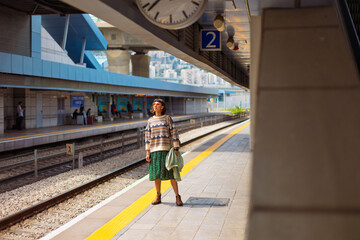 girl standing at the train station waiting for the train. woman with backpack waiting for the train.