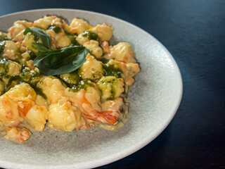 Gnocchi con ricotta e pesto Genovese, ricotta sauce with thin ruffled carrots, Cherry tomatoes and basil, traditional italian recipe, high angle view, close up