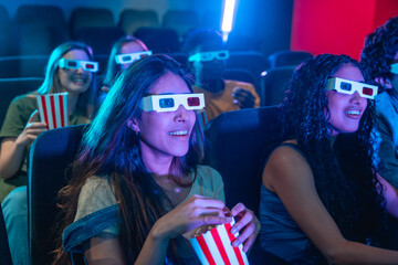 Young people wearing 3d glasses watching a movie and eating popcorn