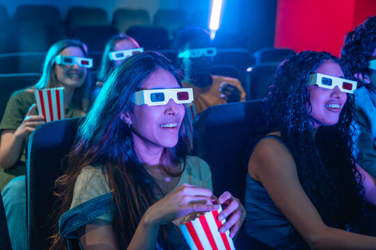 Young people wearing 3d glasses watching a movie and eating popcorn - Powered by Adobe