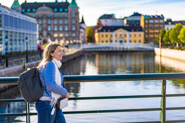Beautiful middle-aged woman tourist sightseeing city center of Malmo on sunny autumn day. City...