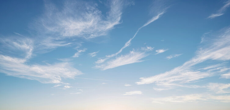 Wide shot of a blue sky with white wispy clouds streaking across it. Background photos for banners, posters and wallpapers.