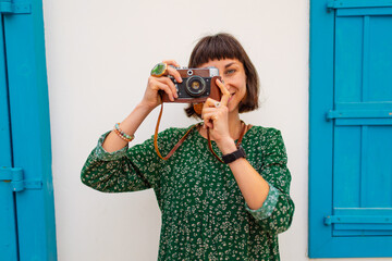 A girl with a camera walks around the city. A tourist enjoys her vacation, taking pictures of the...