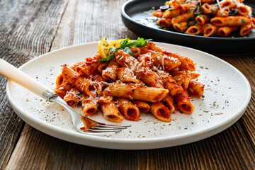 Penne noodles with tomato sauce and parmesan cheese served on wooden table	