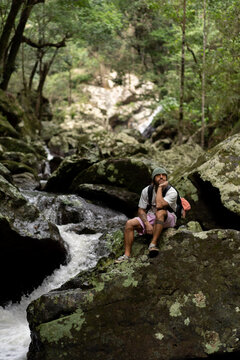 Man sitting over rocks along a waterfall trail in Australia