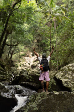 Man stands over rocks along a waterfall trail in Australia