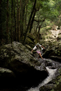 Man hiking over rocks along a waterfall trail in Australia