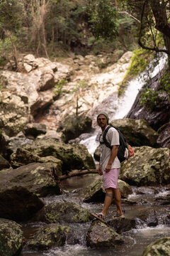 Man standing over rocks along a waterfall trail in Australia