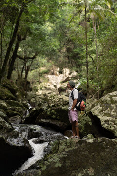 Man stands over rocks along a waterfall trail in Australia