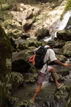 Man hiking over rocks along a waterfall trail in Australia