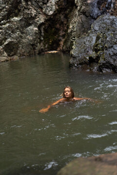 A woman swims in a waterfall