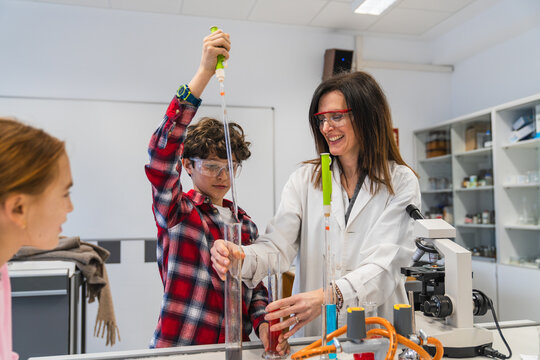 Elementary school students and teacher performing a chemical experiment using test tubes and pipettes in science class