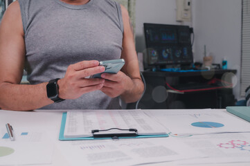 Data Driven Insights Person In Black Smartwatch Studies Data On Smartphone At Home Workspace, Analyzing Charts With Clipboard Monitor Interface