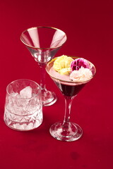 Cocktail glasses with fruit garnish with empty glass glasses on red background
