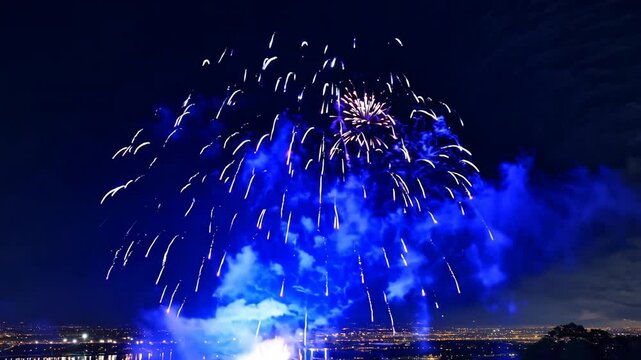 New Year's Eve Fireworks Over the City and River with Bright Glowing Lights in the Night Sky