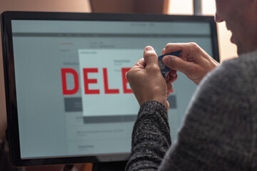 Frustrated stressed man tearing blocked credit card, text delete on computer screen. Man viewing monitor, contemplating account deletion and data removal