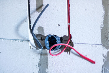 A collection of wires is protruding out from a hole in the wall