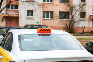 A white taxi vehicle prominently displays an orange sign atop it