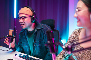 Teenagers, men and women, host podcasts in a room using LED lights, computers, headphones,...