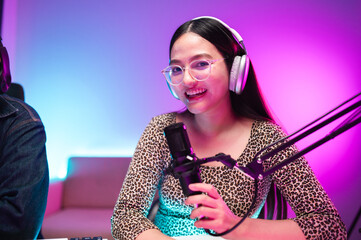 Teenagers, men and women, host podcasts in a room using LED lights, computers, headphones, condenser microphones, and tablets to share their knowledge and experiences through live online broadcasts.