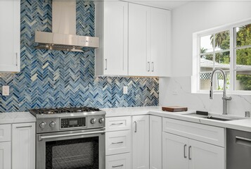 Modern white kitchen with blue tile backsplash, stainless steel appliances, and minimalist cabinetry