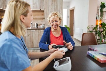 Fototapeta premium Caring conversation between nurse and elderly woman in a cozy home setting