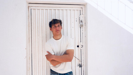 Young handsome man portrait, white metal door on background