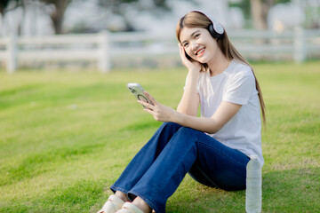 Asian women sit and listen to music in the park.
