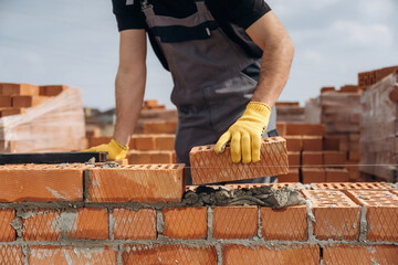 Creating the wall. Close up view of construction man that is working with bricks