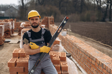 Black colored leveling tool. Construction worker is at job with bricks outdoors
