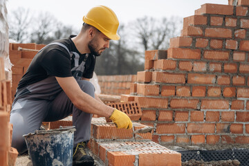 Applying concrete. Construction worker is at job with bricks outdoors