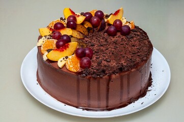 A delectable chocolate cake is topped with fresh fruit and served on a white plate, ready to enjoy.