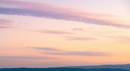 Obraz premium Pastel sky during sunset with soft clouds over mountain range