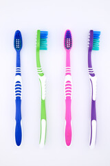 bright multi-colored toothbrushes neatly lined up on white background close-up top view