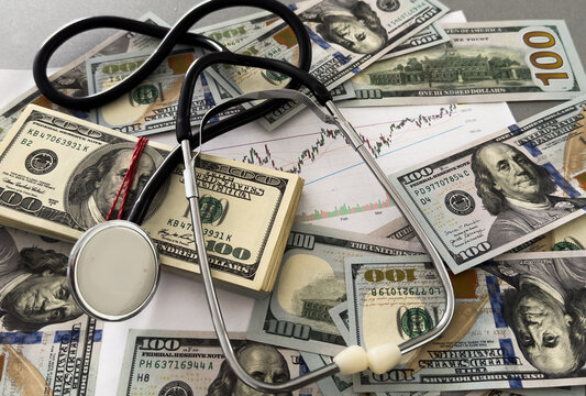  dollar bills and a stethoscope for concepts of health of the economy and cost of healthcare