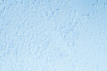 Delicate ice crystals form a beautiful and intricate frosty pattern on a cold window.