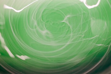 Subtle white swirls dance gently against a calming green canvas, creating a soft and ethereal abstract design.