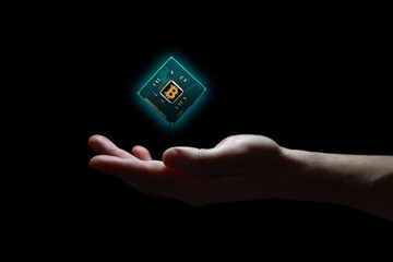 A computer chip hovers above a hand on a black background. The processor has a symbol of the digital currency Bitcoin