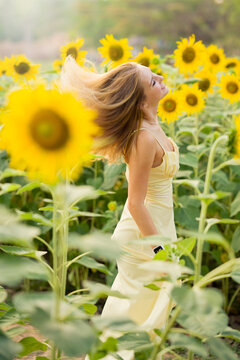 Cute european young model girl posing and having fun in a field full of blooming sun flowers. Showing freedom, innocence and youth