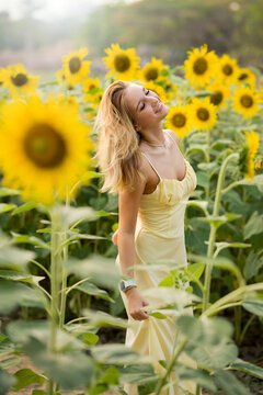 Cute european young model girl posing and having fun in a field full of blooming sun flowers. Showing freedom, innocence and youth