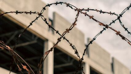 rusty barbed wire fence against the backdrop of an abandoned bui
