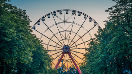 ferris wheel in the park against the blue sky behind trees