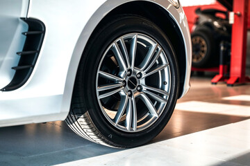 Car Wheel , Close-up of a car wheel with a silver alloy rim and black tire. Focus on car parts, vehicles, and automotive. Indoor shot, possibly in a garage or showroom.